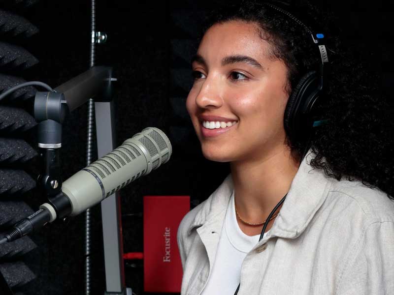 v.c.u. student in a broadcast booth speaking into a microphone and wearing headphones