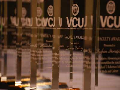 a row of plaques for robertson school faculty awards inscribed with student recipient names